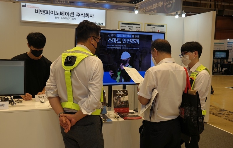  비앤피이노베이션 관계자가 방문객에게 스마트 안전조끼에 대해 설명하고 있다. <사진 : 헬로티>