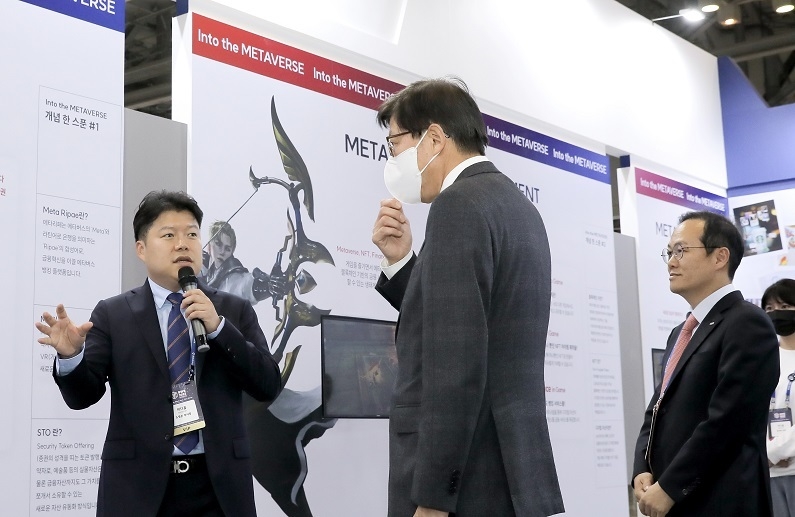 박형준 부산시장(가운데)이 ‘BWB2022’에 참가한 미디움-BNK부산은행 공동전시관에서 조영준 미디움 부사장(왼쪽)과 BNK부산은행 김상환 상무(오른쪽)의 전시관 설명을 듣고 있다. (제공; 미디움)