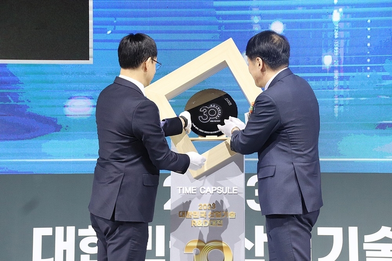 전윤종 한국산업기술기획평가원 원장(좌), 장영진 산업통상자원부 제1차관(우)이 30주년 기념패를 타입 캡슐에 장착하고 있다. (출처 : 헬로티)