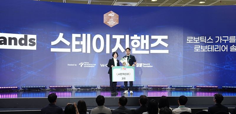 윤세용 스테이지핸즈 대표(우)가 스마트라이프위크 2025(Smart Life Week 2025) 부대행사로 열린 '시민혁신상(Citizen Innovation Award)'에서 수상을 기념하고 있다. 좌측은 시상자로 무대에 오른 강옥현 서울시 디지털도시국장. (출처 : 스테이지핸즈) 