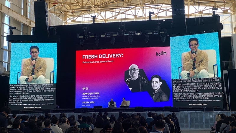 미국 뉴욕 브루클린에서 열린 UKF KOOM 2025 행사에서 연사와 청중이 플리토 라이브 트랜스레이션을 통해 글로벌 소통하고 있다. (출처:플리토)